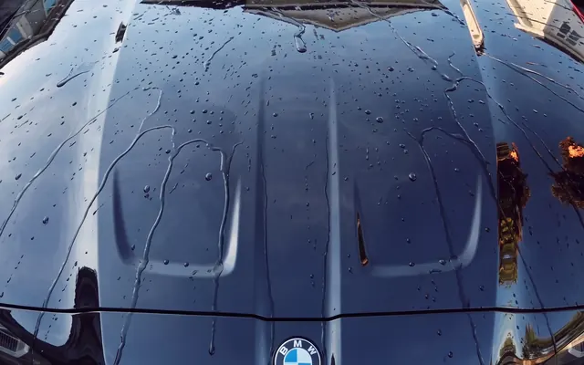 Water beading on the ceramic-coated hood of a black BMW M4