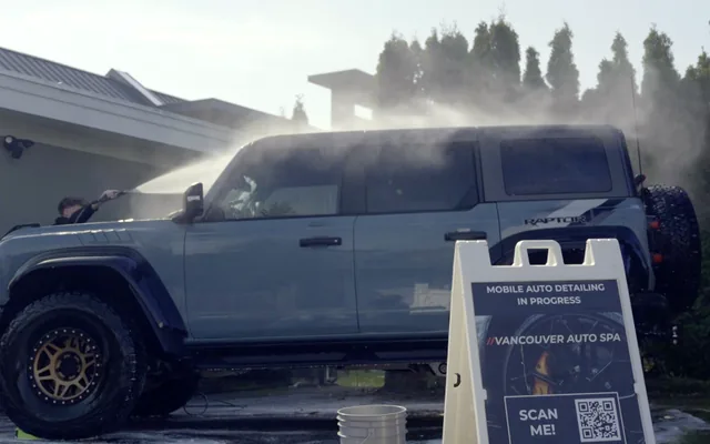Vancouver Auto Spa washing a Ford Bronco Raptor in a client's driveway, with the VAS sign out front