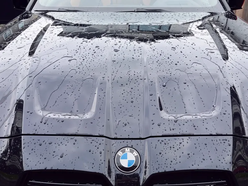 Rain beading across the coated hood of a black BMW M4